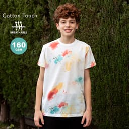 A boy models a white T-shirt with colourful splashes of red, blue, and yellow against a green background.