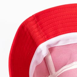 A red brim hat with a white lining, showcasing stitching details and an internal structure.