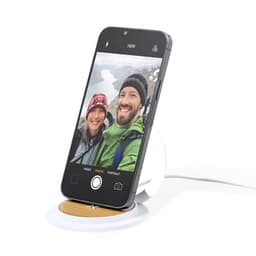 A wireless charger with a wooden base and a white stand, featuring a smartphone displaying a selfie.