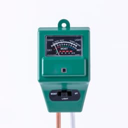 A moisture meter with a green body, featuring a dial gauge for measuring moisture levels and a pH indicator.
