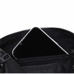 A black Koket Bag featuring a zippered compartment with a smartphone visible inside.