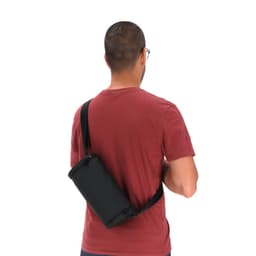 A black sling bag is worn across the body by a person with short hair, facing away from the camera.