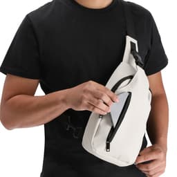 A person wearing a black shirt holds a white Soplex Bag, which features a zippered pocket. The bag includes a logo.