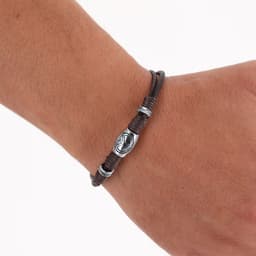 A brown leather bracelet with silver beads and a decorative charm, displayed on a hand.