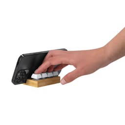 A phone holder with a wooden base and white keys, designed to support a smartphone in an upright position.