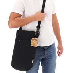 A black Harkal bag is being held by a person, featuring a shoulder strap and an outer pocket.