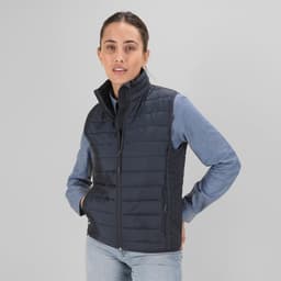 A navy puffer vest with a high collar, featuring a zip front and side pockets. The model wears a denim shirt underneath.