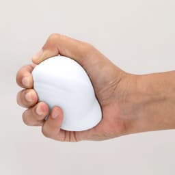 A white stress ball is being squeezed in a hand, designed for stress relief and relaxation.