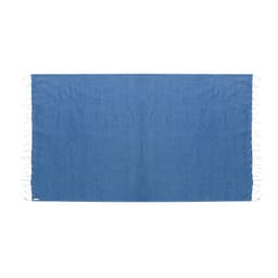 A blue beach towel featuring white tassels on the edges and a logo in the corner.