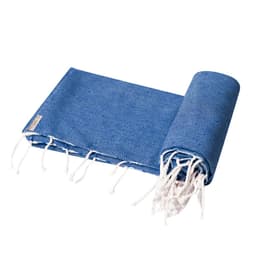 A blue towel, rolled and slightly unfolded, featuring white tassels at one end and a logo on the side.