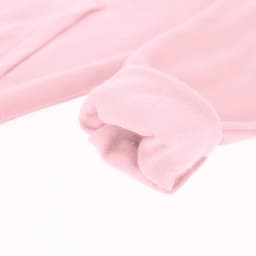 A pink hoodie with a soft texture, showcasing the cuff detail of the sleeve. It features a logo on the garment.