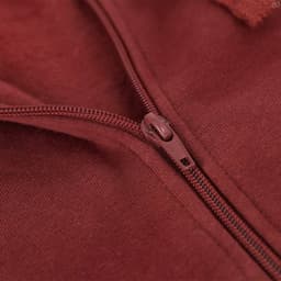 A close-up of a maroon hoodie featuring a zip with a metallic pull tab and soft fabric texture.
