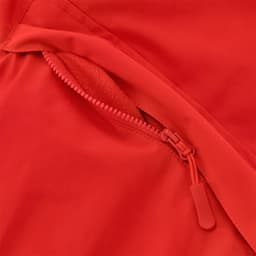 A close-up of a red puffer jacket featuring a zipped pocket with a soft lining. The jacket has a logo.