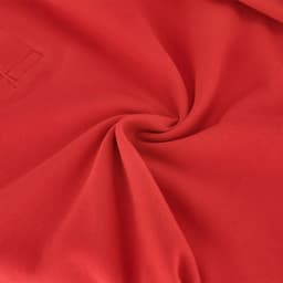 A close-up view of a red polo shirt fabric, featuring a subtle texture and a small logo.