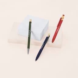 Three Kiner ballpoint pens in green, red, and blue, displayed on a light coloured surface with a white box.