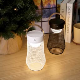 A white and a black portable lamp with a mesh design, featuring handles and soft light, placed on a wooden surface.