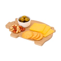 A wooden chopping board shaped like a pig, featuring cheese slices, crackers, nuts, and olives in a bowl.