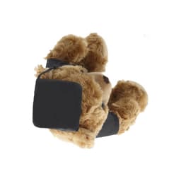 A plush brown teddy bear wearing a black band around its waist, with a small tag attached.