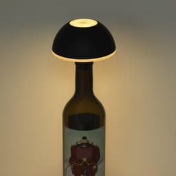 A black lamp with a dome-shaped top sits atop a wine bottle, emitting a soft glow.
