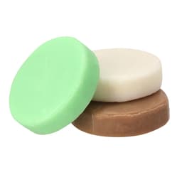 Three round soaps in green, white, and brown colours, stacked together, with a simple branding logo visible.