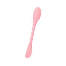 A pink beauty tool with two functions: a bristle side and a smooth side for application or exfoliation.