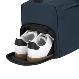 A navy duffle bag featuring a side compartment with a pair of white sneakers with black accents.