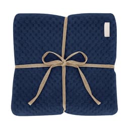 A navy blue blanket tied with a natural-coloured ribbon, featuring a textured pattern. It has a small logo on the edge.