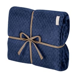 A folded navy blue Iridian blanket tied with a natural twine bow, featuring a textured pattern. It has a branding label.