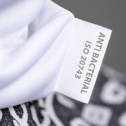 A close-up of a white scarf with a label indicating "Anti Bacterial" and related information.