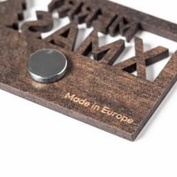 A wooden magnet with a dark brown finish, featuring cut-out letters and a circular magnet on the reverse side.