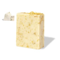 A block of soap with a creamy colour and dried flowers embedded, alongside a small fabric bag.