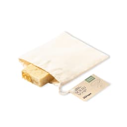 A solid soap bar with a natural appearance inside a drawstring pouch, featuring a tag and a piece of dried plant material.