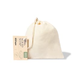 A cream-coloured drawstring pouch containing solid soap, featuring a tag. The pouch has a simple, unbranded design.