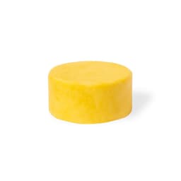 A round, yellow solid product with a smooth surface, likely a hair or beauty treatment. It has a simple design without branding.