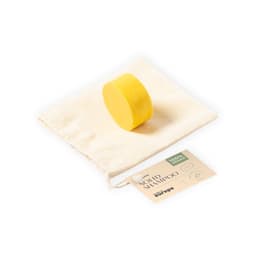 A round yellow solid shampoo bar on a cream coloured pouch, accompanied by a tag with branding.