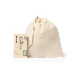 A cream-coloured drawstring bag containing solid shampoo, with a tag attached and branding visible.