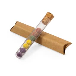 A test tube containing colourful chocolate balls, resting on a brown cardboard sleeve. The colours include purple, yellow, and red.