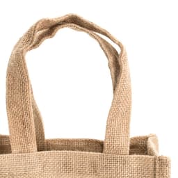A tan jute bag with two sturdy handles and a textured surface. It features a simple design with no visible branding.