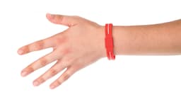 A red energy bracelet worn on a hand, featuring a simple design and an attached strap.