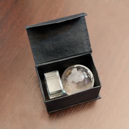A black gift box containing a globe paperweight and a silver cube. The globe features a world map design.
