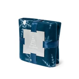 A folded teal blanket with a snowflake pattern, neatly tied with a satin ribbon and a branded label.