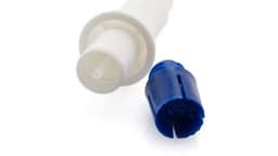 A blue component of a vaporizer next to a white connector attachment. The image has a blurred background.