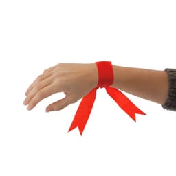 A red ribbon tied around a wrist, featuring two flowing ends. The hand is positioned against a neutral background.