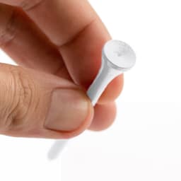 A white golf tee held between fingers, featuring a smooth surface and a rounded top.