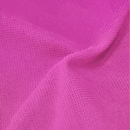 A textured pink towel with a soft fabric finish, featuring subtle variations in shade and a logo.