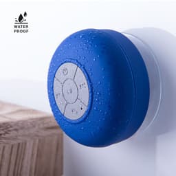 A waterproof Bluetooth speaker in vibrant blue, featuring buttons on its surface and water droplets.