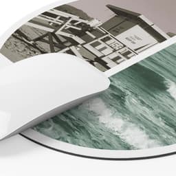 A circular mouse pad featuring a black and white image of a lifeguard station and a colour depiction of ocean waves.