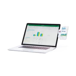 A laptop with a phone stand attached, holding a smartphone displaying graphs and charts. The laptop is silver.