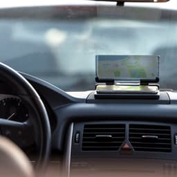 A car phone holder displaying a smartphone with a map on the dashboard, featuring a sleek, modern design.