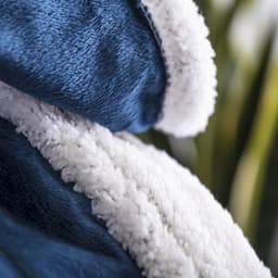 A plush navy blue blanket with a fluffy white interior, featuring a soft texture and gentle folds.